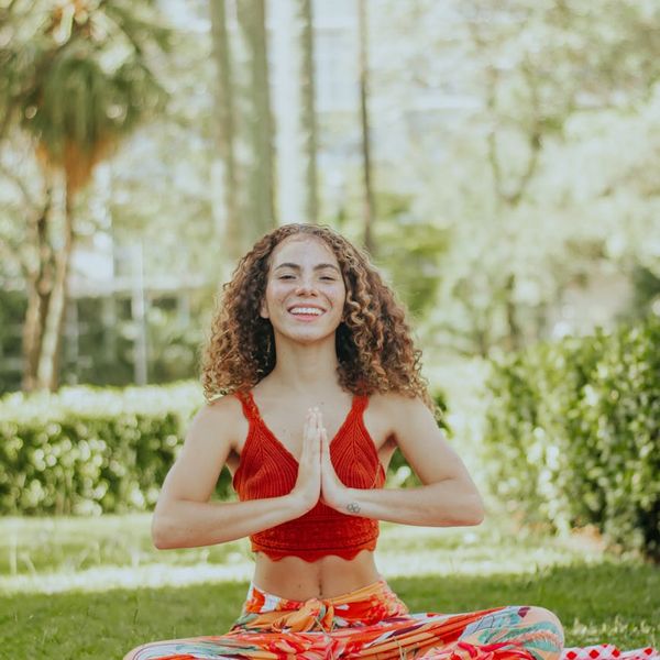 Smiling pregnant woman meditating on a yoga mat in a bright room.
